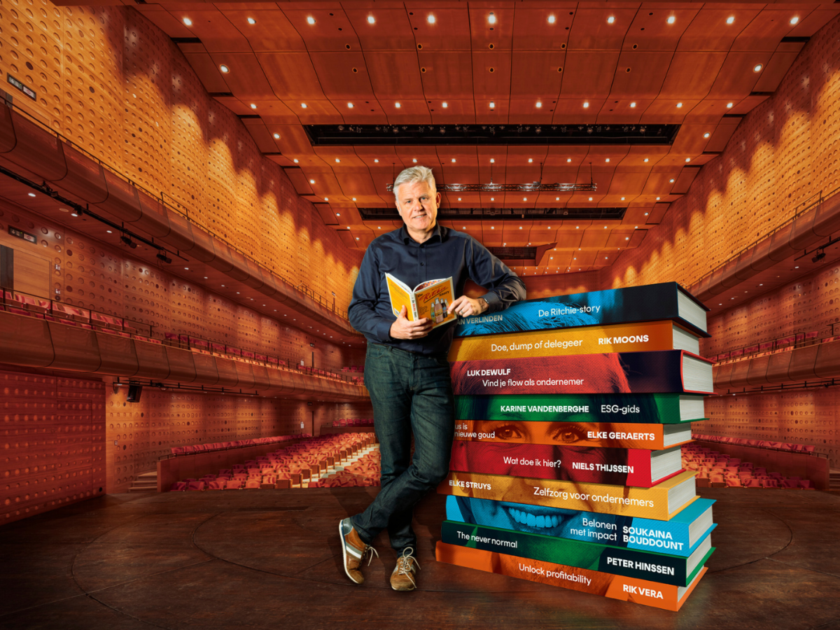 Ondernemer Jan Verlinden leunt op een stapel boeken.